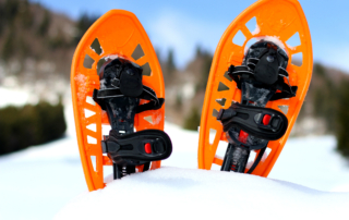 Orange snowshoes for walking on the white snow and blue sky